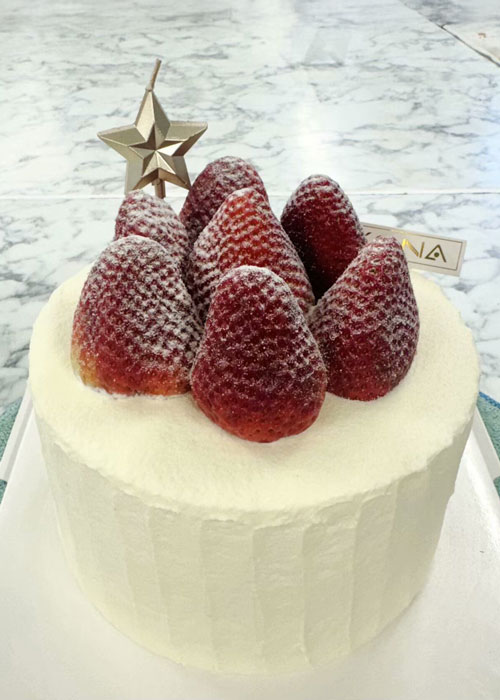 White-iced cake topped with strawberries dusted with icing sugar.
