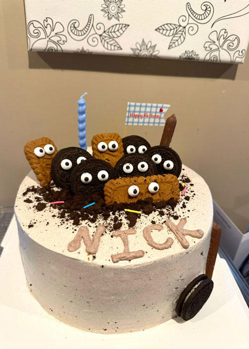 Round birthday cake covered with cookies and cream icing and topped with cookies with eyes.